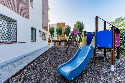 a playground with a blue slide next to a building at Apartamentos Sunway Amapola in Sitges