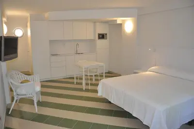 a bedroom with a bed and a table and a kitchen at Apartamentos Sunway Amapola in Sitges