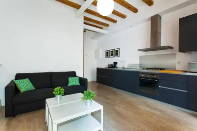 a living room with a black couch and a kitchen at Gracia Terrace in Barcelona