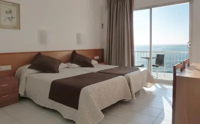 a bedroom with a bed and a large window at Gran Sol Hotel in San Pol de Mar
