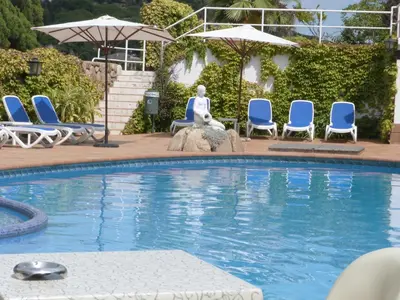 a swimming pool with chairs and a statue in the middle at Gran Sol Hotel in San Pol de Mar