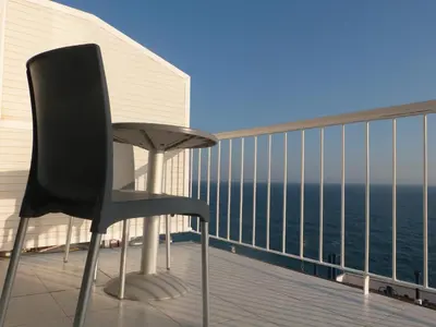 a black chair sitting on a balcony overlooking the ocean at Gran Sol Hotel in San Pol de Mar