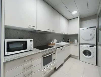 a white kitchen with a microwave and a washer and dryer at Stay Unique Apartments Diagonal III in Barcelona