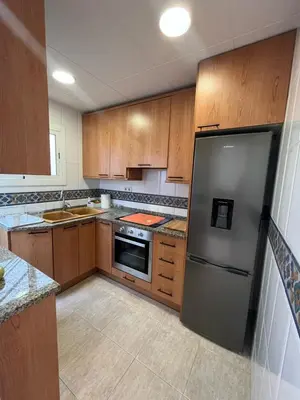 a kitchen with wooden cabinets and a stainless steel refrigerator at Apartamento St Zenon in Arenys de Mar