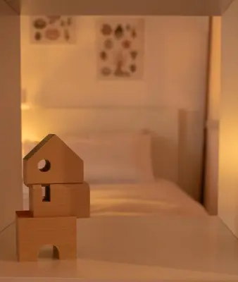 a toy house is sitting in front of a bed at MonResidence La Figuereta in Manresa