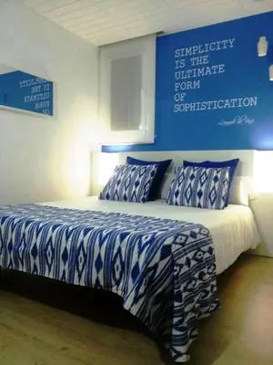 a bedroom with a blue and white bed with pillows at Petit Hotel in Barcelona