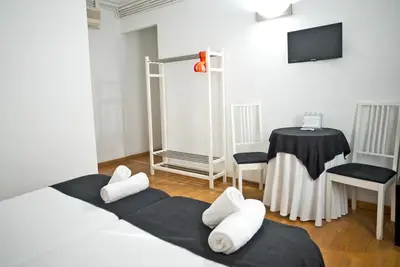 a bedroom with a bed with white pillows and a table at Petit Hotel in Barcelona