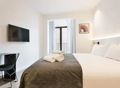 a bedroom with a large bed with a teddy bear on it at Vale Suites in Barcelona
