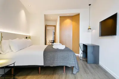 a hotel room with a bed and a flat screen tv at Vale Suites in Barcelona