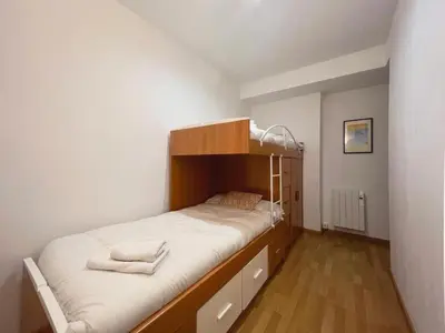 a bedroom with a bunk bed with white sheets at Hauzify I Apartament Can Reig in San Pol de Mar