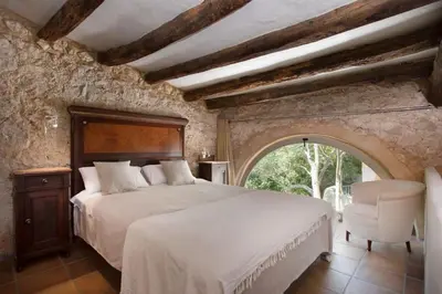 a bedroom with a large bed and a chair at Sitges Hill Retreats-Masia Nur 22 bedrooms divided over 9 houses for max 44 guests in Canyelles
