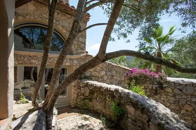 a stone house with a tree in front of it at Sitges Hill Retreats-Masia Nur 22 bedrooms divided over 9 houses for max 44 guests in Canyelles