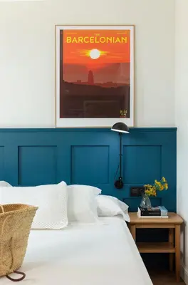 a bed with a blue headboard with a picture above it at Som Nit Port Vell in Barcelona