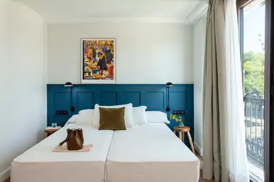 a bedroom with a large white bed with a blue wall at Som Nit Port Vell in Barcelona