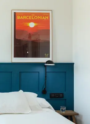 a bed with a blue headboard with a picture above it at Som Nit Port Vell in Barcelona