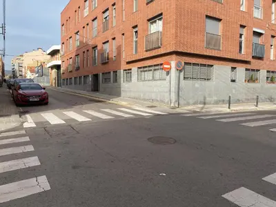 an empty street with a red car parked in front of a brick building at Oasis familiar Terrassa in Terrassa