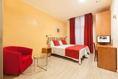 a hotel room with a bed and a red chair at Alba Hotel in Barcelona