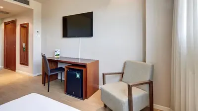 a room with a desk and a chair and a television at Sercotel Ciutat de Montcada in Montcada i Reixac