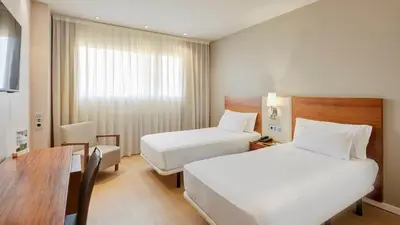 a hotel room with two beds and a desk at Sercotel Ciutat de Montcada in Montcada i Reixac