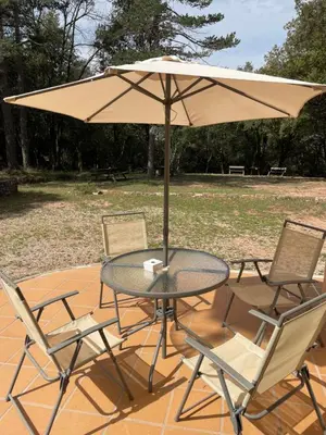 a table and chairs with an umbrella on a patio at Refugio en el Parque natural del Montseny in El Brull