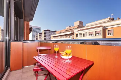 a red table with two glasses of wine on a balcony at Sweett - Casa Fira in Barcelona