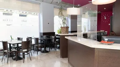 a restaurant with a counter and tables and chairs at Hotel Coronado in Barcelona