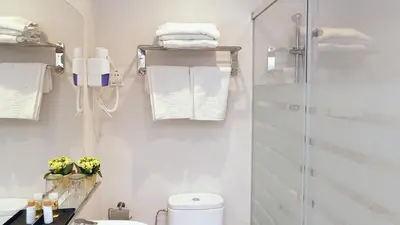 a bathroom with a shower and a toilet and towels at Hotel Coronado in Barcelona