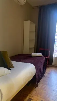 two beds in a room with a window and a table at Somnio Hostels in Barcelona