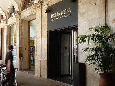 a man walking past a building with a sign on it at Roma Reial in Barcelona