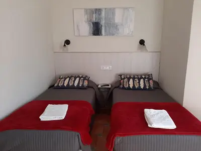 two twin beds in a small room with red blankets at Casa Consell Gran Via, Guest House in Barcelona