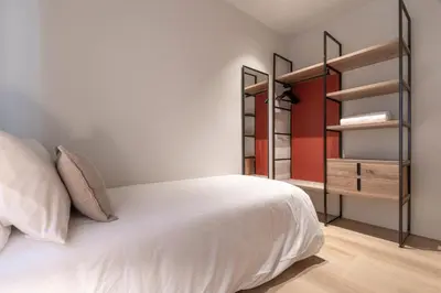 a bedroom with a white bed and open shelves at Arrivo Apartments in Barcelona
