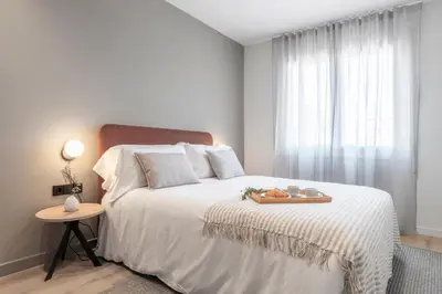 a white bedroom with a large bed with a tray on it at Arrivo Apartments in Barcelona