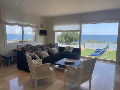 a living room with a couch and a table and chairs at Villa Farell just in front of the sea in San Pol de Mar