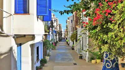 an alley between two buildings with flowers and blue shutters at EMILY BEACH-CITY Apartment in Montgat