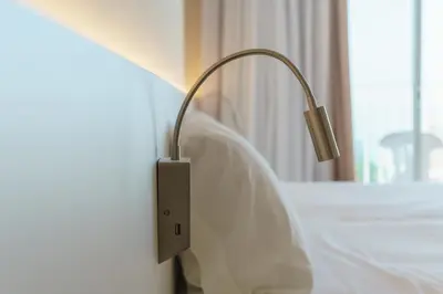 a lamp on the side of a bed in a room at Checkin Catalonia in Calella