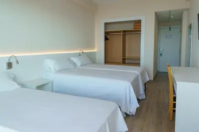 two beds in a hotel room with white sheets at Checkin Catalonia in Calella