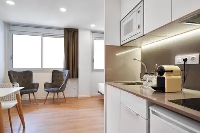 a kitchen and living room with a table and chairs at Aparthotel Augusta in Barcelona
