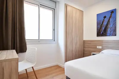 a bedroom with a bed and a desk and a window at Aparthotel Augusta in Barcelona