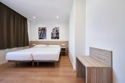 a bedroom with two beds and a bench in it at Aparthotel Augusta in Barcelona