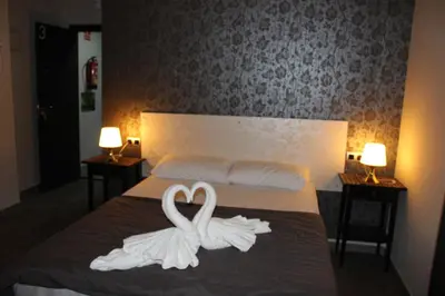 two white swans are sitting on a bed at BCN Condal Hostal in Barcelona