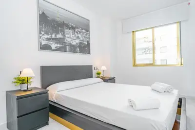 a white bedroom with two beds and a window at HomeHolidaysRentals Cyan- Costa Barcelona in Pineda de Mar