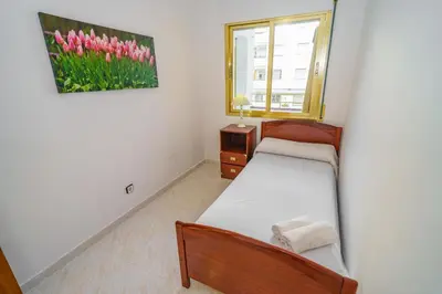 a bedroom with two beds and a window with pink tulips at HomeHolidaysRentals Cyan- Costa Barcelona in Pineda de Mar