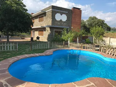 a pool in front of a house with a sign on it at Casa L'Avi in Palau-Solità i Plegamans
