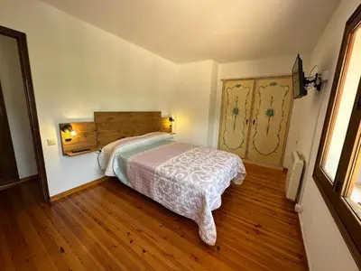 a bedroom with a bed and a wooden floor at Casa L'Avi in Palau-Solità i Plegamans