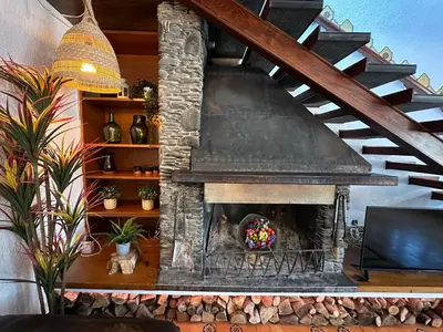 a stone fireplace in a living room with a staircase at Casa L'Avi in Palau-Solità i Plegamans