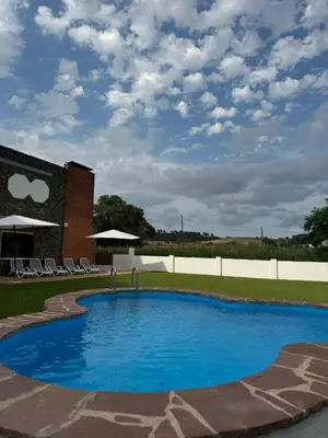 a large blue pool with chairs and a building at Casa L'Avi in Palau-Solità i Plegamans