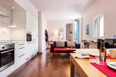 a kitchen and living room with white cabinets and a table at Bed&BCN Diagonal 2 in Barcelona