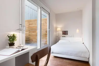 a bedroom with a bed and a desk with a window at Bed&BCN Diagonal 2 in Barcelona