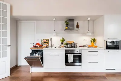 a kitchen with white cabinets and black appliances at Bed&BCN Diagonal 2 in Barcelona