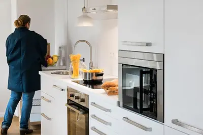a woman is standing in a kitchen with a sink at Bed&BCN Diagonal 4 in Barcelona